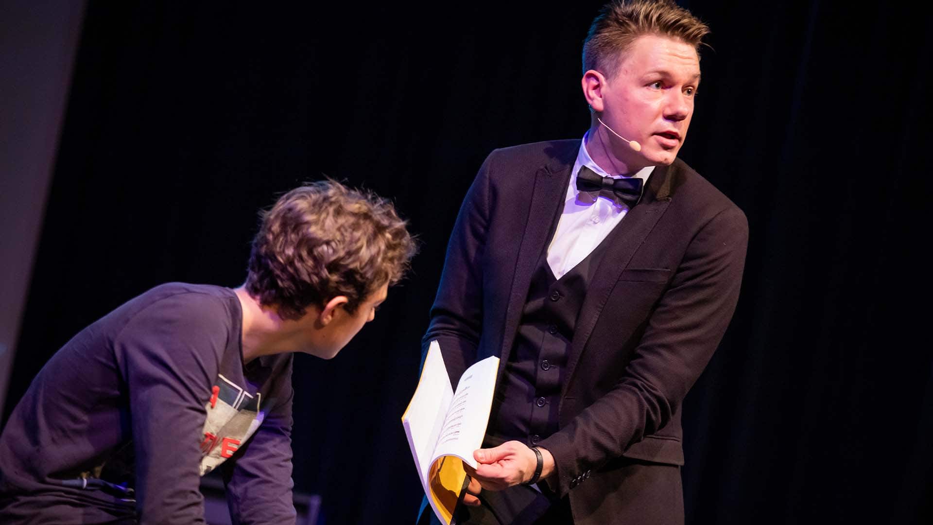 Ein Zuschauer blättert in einem Buch auf der Bühne