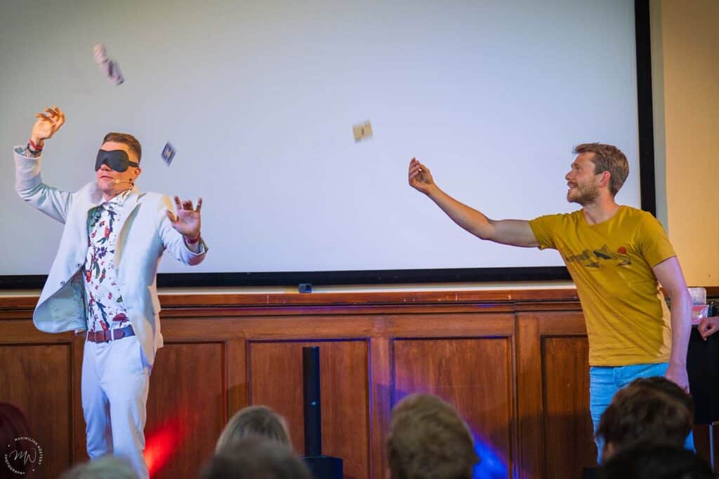 Ein Zuschauer wirft Karten in die Luft, während Thomas versucht, eine zu fangen.