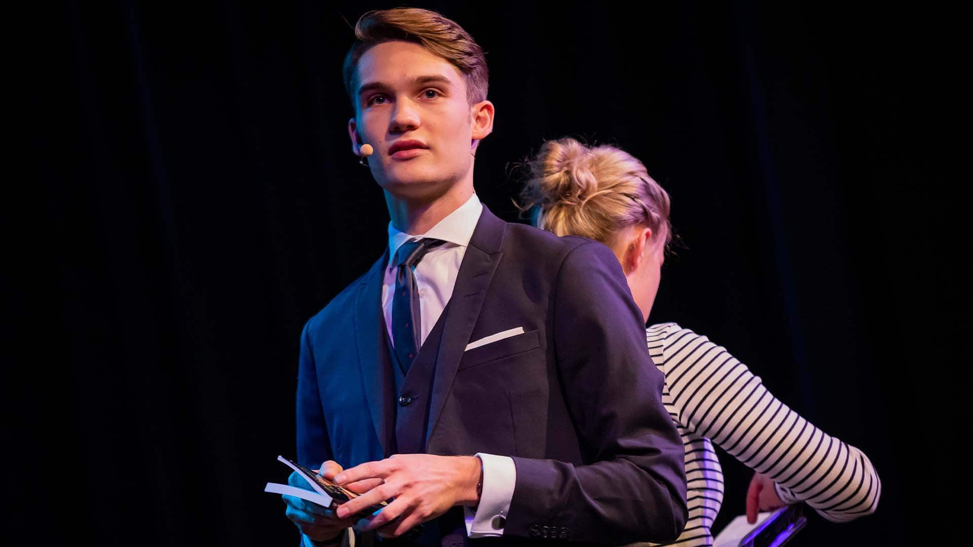 Vincent und eine Zuschauerin stehen Rücken an Rücken mit je einem Buch in der Hand