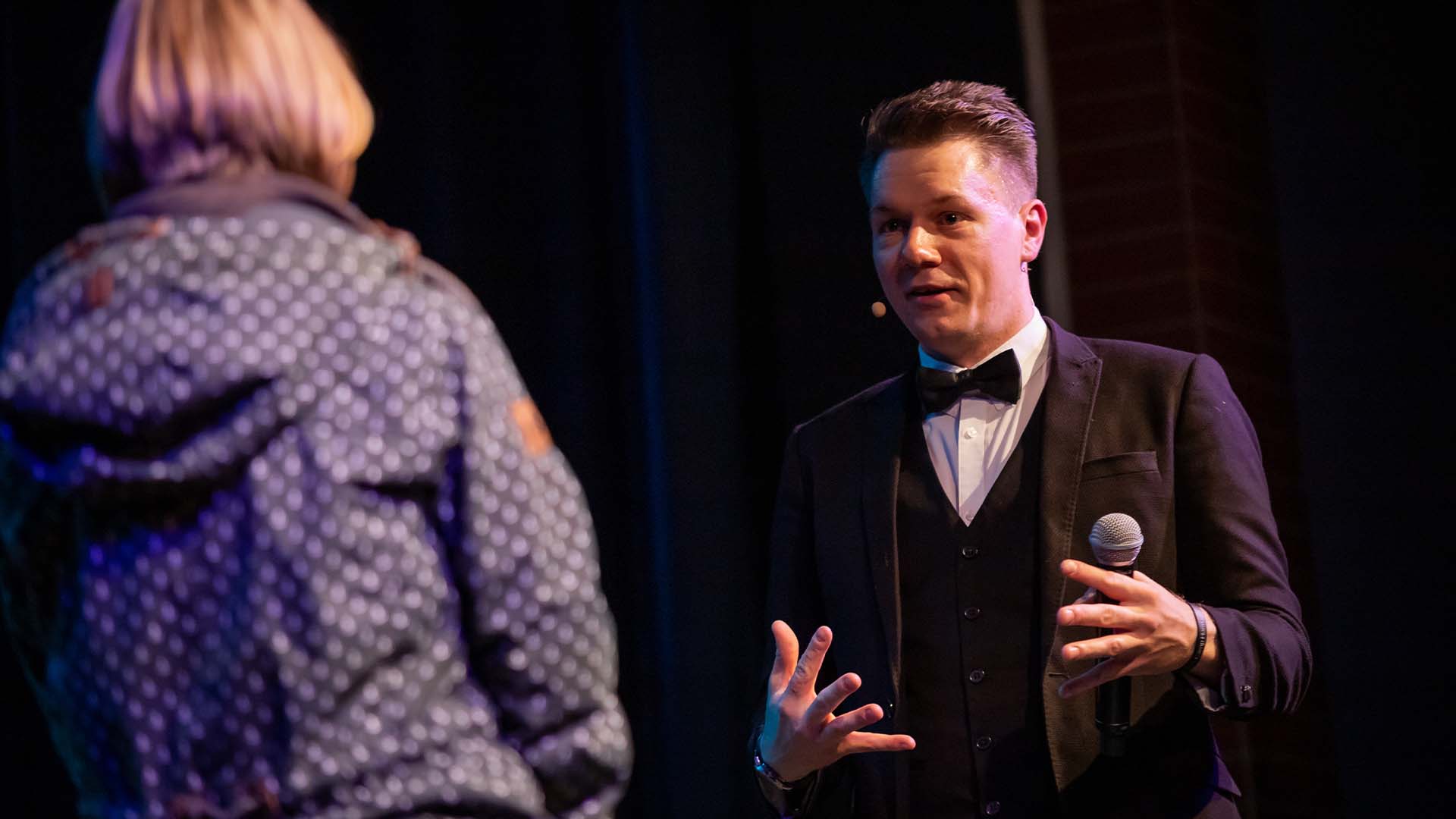 Thomas Majka erklärt einer Zuschauerin auf der Bühne etwas