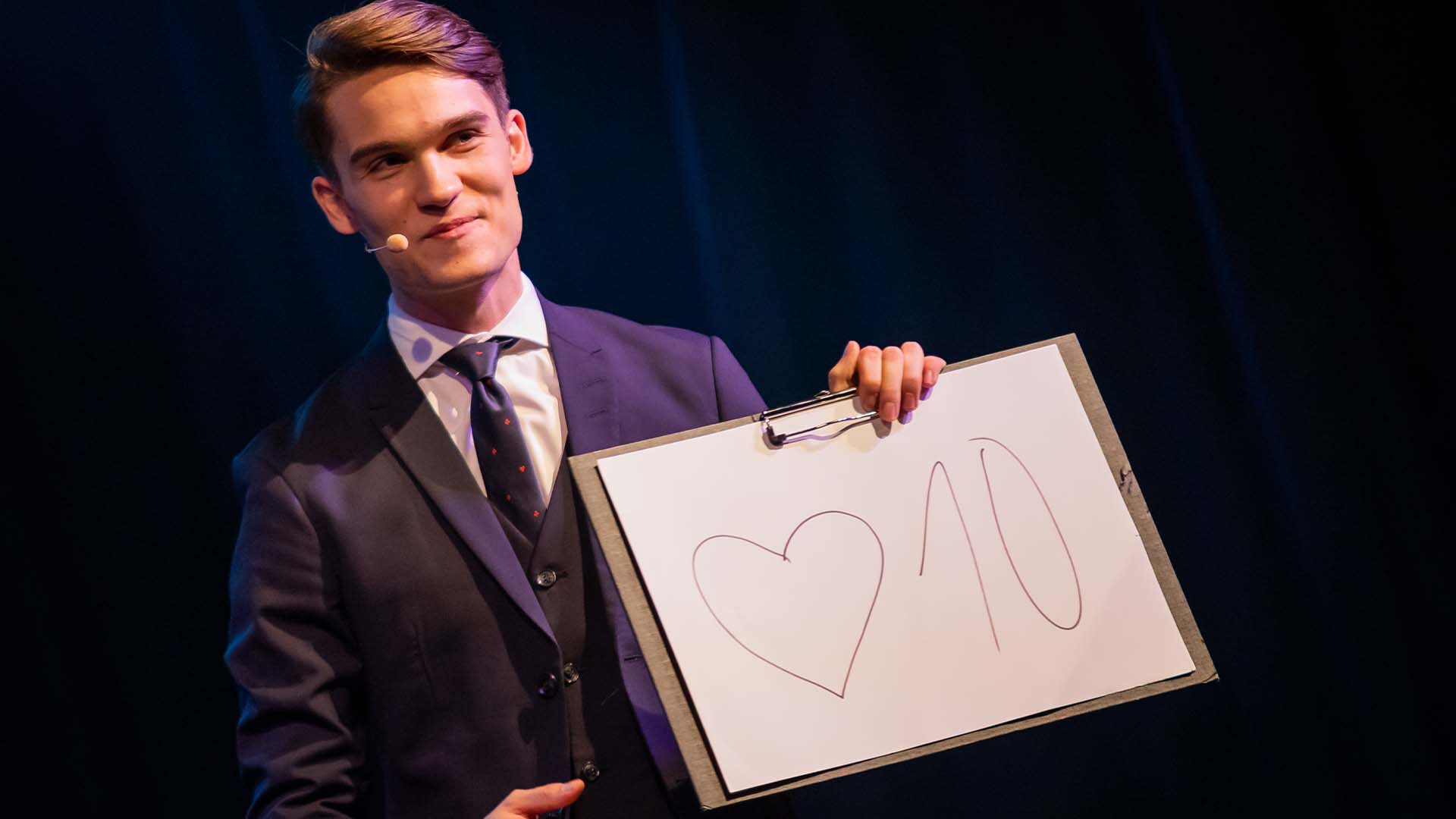 Vincent Frommer hält einen Block mit der Aufschrift „Herz 10“