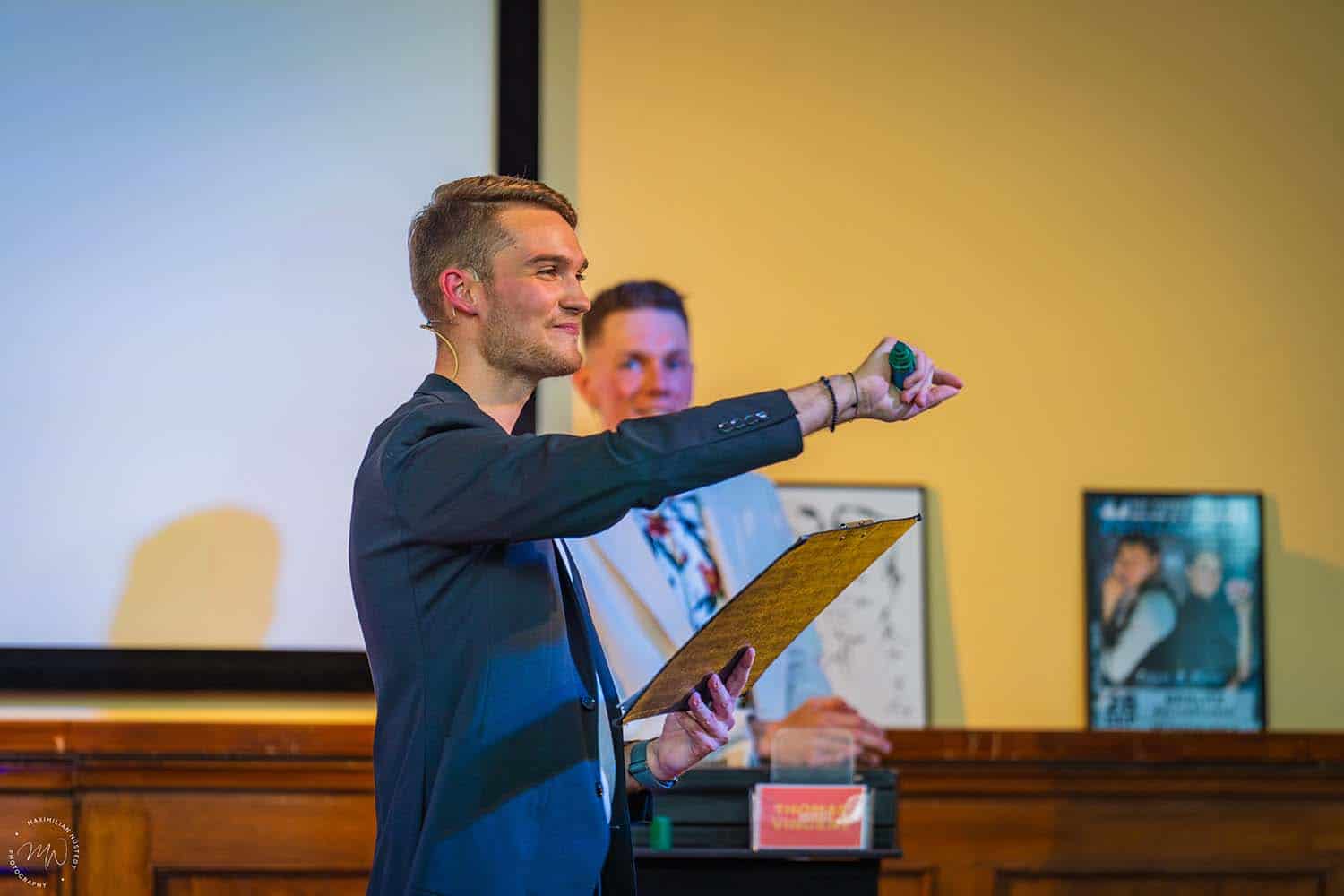 Vincent erklärt dem Publikum einen Trick oder Ablauf.