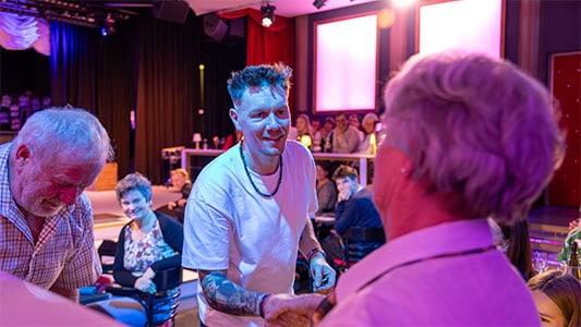 Thomas Majka reicht einem Gast im Zuschauerraum die Hand während der Show im Carte Blanche Petit Theater Dresden