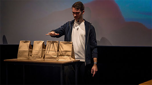 Vincent Frommer hält eine Hand nach vorne ausgestreckt, vor ihm stehen vier Tüten während der Mindtrix-Show in Bautzen