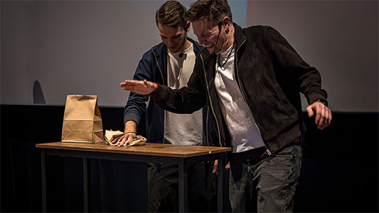 Thomas Majka und Vincent Frommer schlagen auf eine Tüte, während Thomas ängstlich die Hand zurückzieht während der Mindtrix-Show in Bautzen