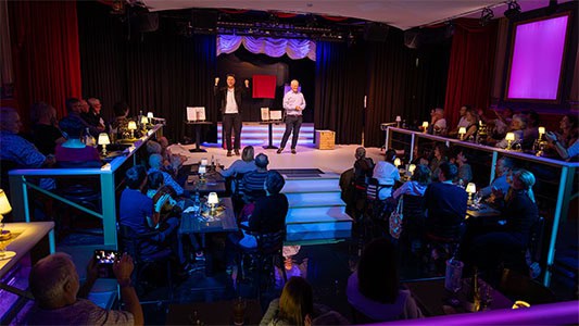 Thomas Majka jubelt auf der Bühne im Carte Blanche Petit Theater Dresden, während ein Zuschauer neben ihm steht