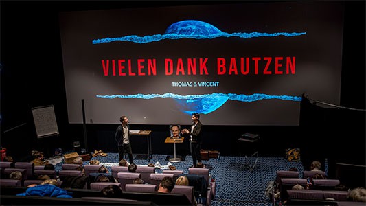 Thomas Majka und Vincent Frommer verabschieden sich auf der Bühne, während auf der Leinwand im Hintergrund vielen Dank Bautzen steht