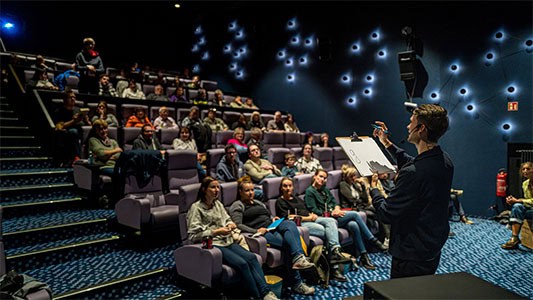 Vincent Frommer schreibt etwas auf, während im Hintergrund das gesamte Publikum der Mindtrix-Show in Bautzen zu sehen ist