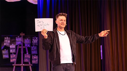 Thomas Majka hält eine Karte mit der Aufschrift das wusste ich während der Show im Carte Blanche Petit Theater Dresden hoch