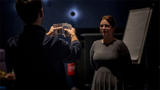 Vincent Frommer hält mehrere Karten in der Hand, während eine Zuschauerin aufmerksam darauf schaut während der Mindtrix-Show in Bautzen