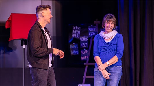 Thomas Majka und eine Frau lachen herzlich miteinander während der Show im Carte Blanche Petit Theater Dresden