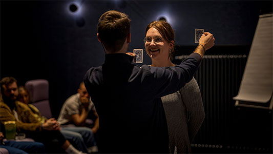Eine Zuschauerin lacht, während Vincent Frommer nur noch zwei Karten in der Hand hält während der Mindtrix-Show in Bautzen