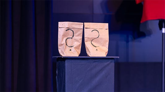 Zwei Papiertüten mit großen Fragezeichen während der Show im Carte Blanche Petit Theater Dresden