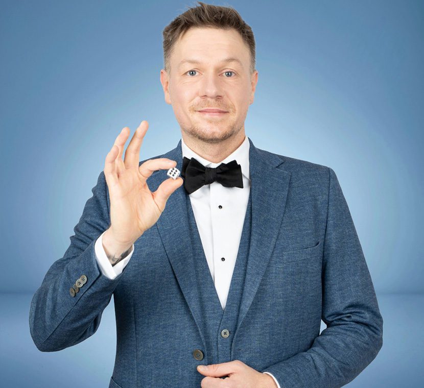 Zauberer Thomas Majka zeigt Würfel bei Mentalmagie und blickt in die Kamera