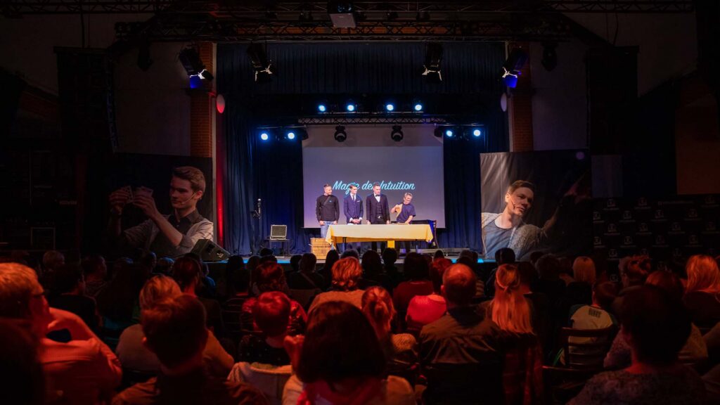 Thomas Majka und Vincent Frommer auf einer großen Bühne mit zwei Zuschauern während einer interaktiven Zaubershow vor großem Publikum