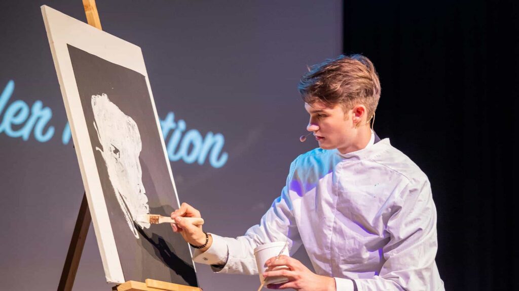 Vincent Frommer zeichnet auf einer Leinwand während einer interaktiven Mentalmagie Show in Berlin