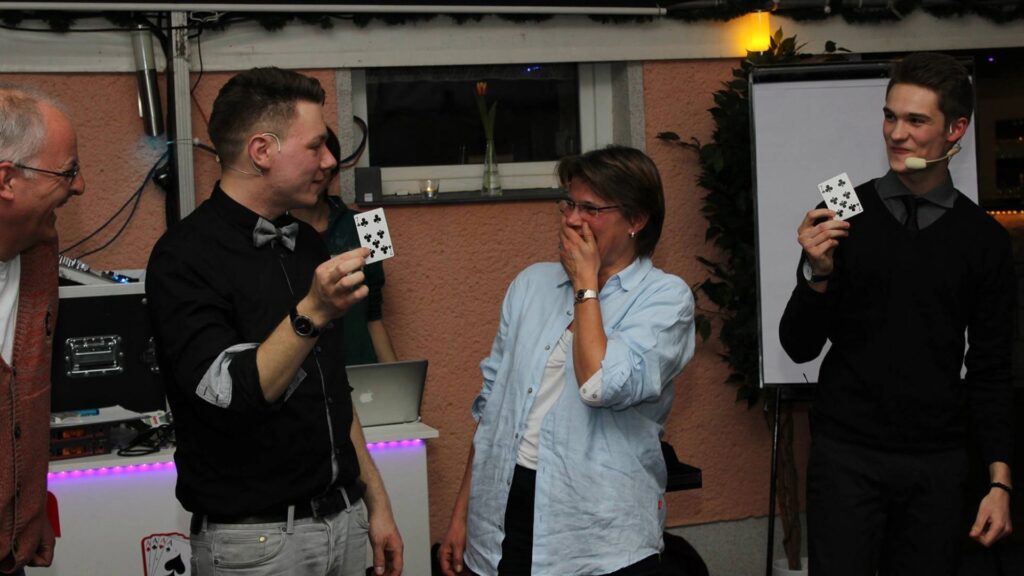 Zwei Zuschauerinnen lachen gemeinsam mit Thomas Majka und Vincent Frommer während einer interaktiven Zaubershow