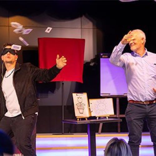 Ein Zuschauer wirft ein Kartenspiel in die Luft, während Thomas Majka mit verbundenen Augen auf der Bühne im Carte Blanche Petit Theater Dresden steht Mentalist Leipzig