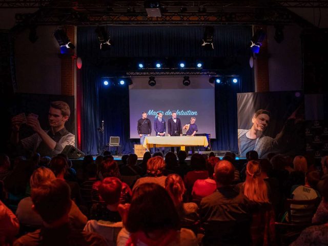Blick aus dem Publikum auf die Bühne mit zwei Zuschauern bei der Show „Magie der Intuition“