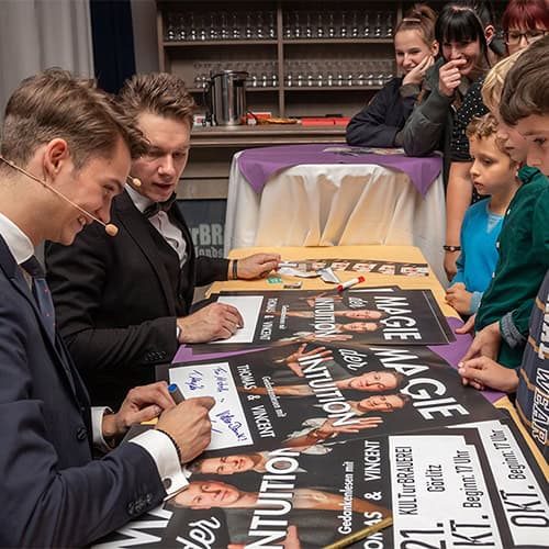 Vincent Frommer und Thomas Majka sitzen am Autogrammtisch bei einer öffentlichen Show