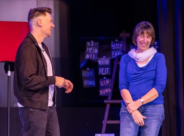 Thomas Majka auf der Bühne mit einer lachenden Zuschauerin während einer interaktiven Zaubershow